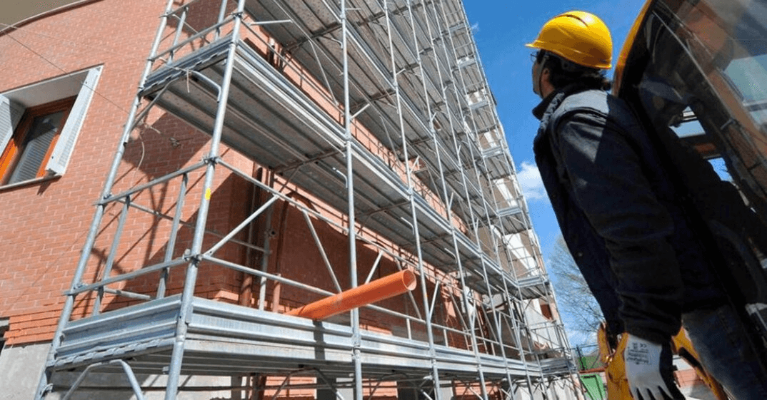 Superbonus, che problemi per le aziende: un ingegnere con caschetto osserva un'impalcatura
