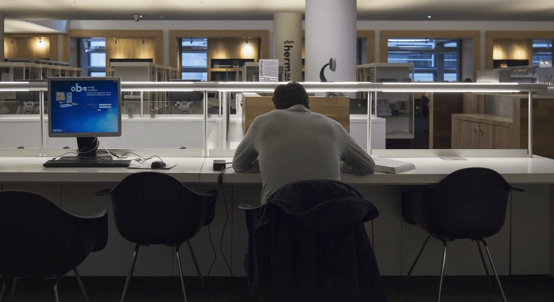 Dipendenza da lavoro, un professionista in ufficio a tarda ora, di spalle, da solo