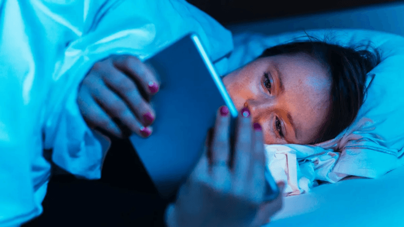 Una donna fa binge watching di serie tv a letto a tarda notte