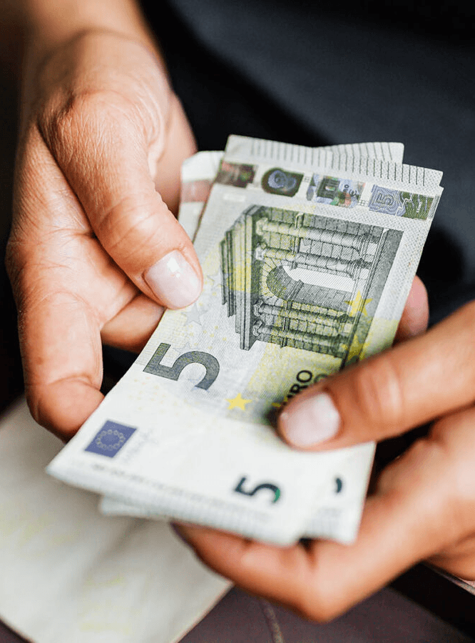 Potremmo permettercelo? Un uomo si appresta a pagare con banconote da 5 euro