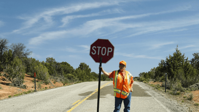 Caldo estremo, un lavoratore con un cartello "stop" sotto il sole cocente, sulla strada