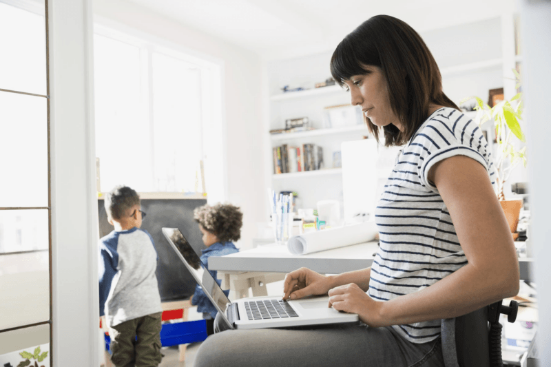 Cyber casalinghe: una donna a casa con i figli davanti al portatile