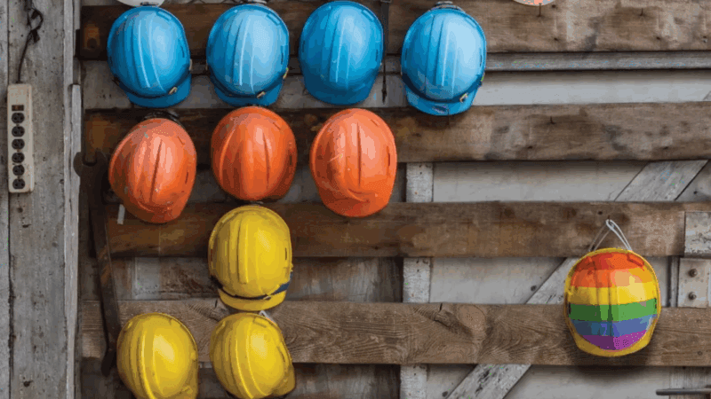 DEI, Diversità, Equità e Inclusione: caschetti colorati isolano un caschetto arcobaleno