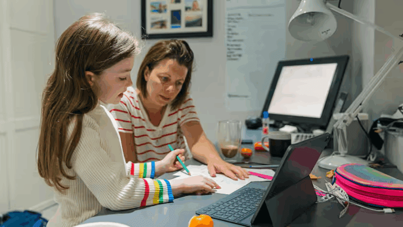 Caregiver in smart working: una madre con una figlia lavora al pc da casa