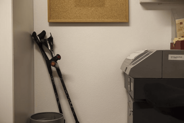 Sclerosi multipla al lavoro: delle stampelle abbandonate vicino a una stampante